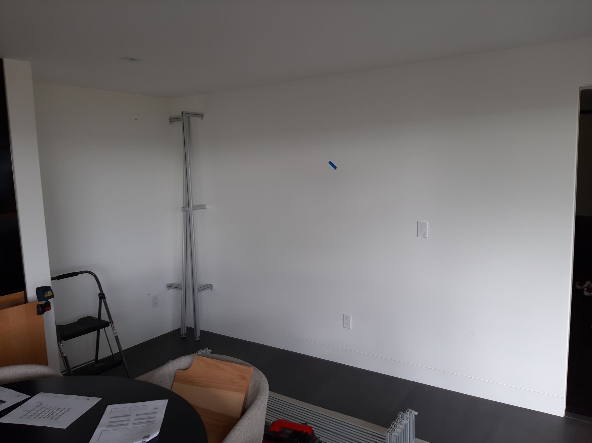 A living room with a white wall and a table and chairs.