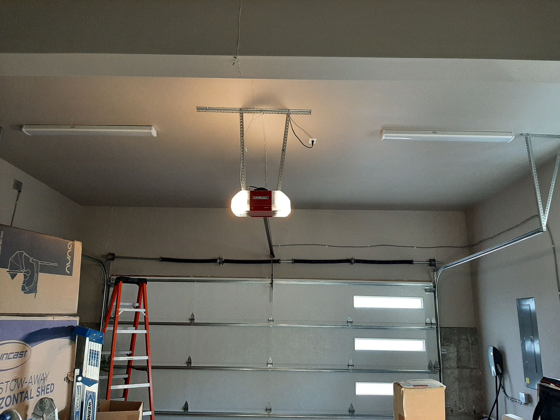 A garage with a red garage door opener hanging from the ceiling.