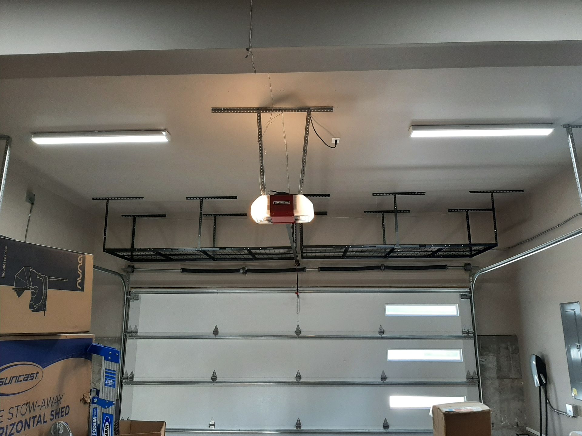 A garage with a garage door open and boxes on the floor.