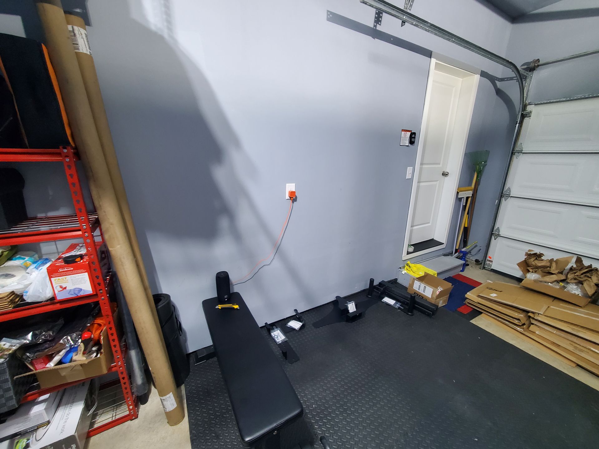 A gym in a garage with a bench and a door.
