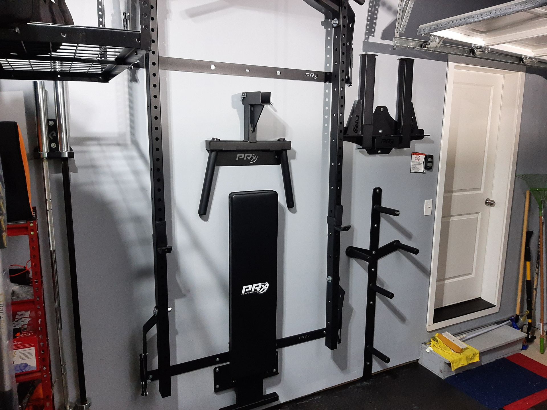 A gym with a bench and a barbell rack on the wall.