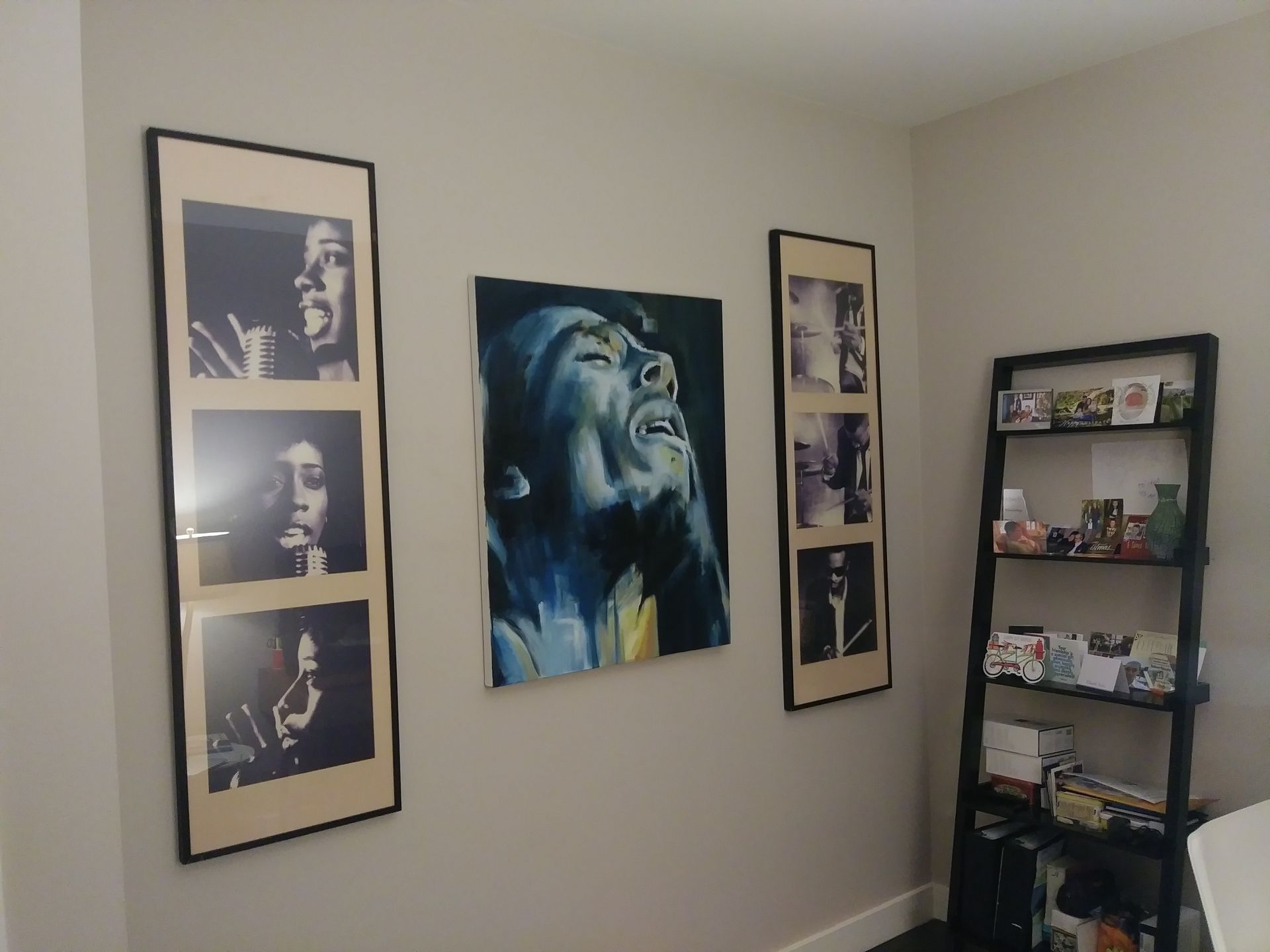 A room with three paintings on the wall and a bookshelf