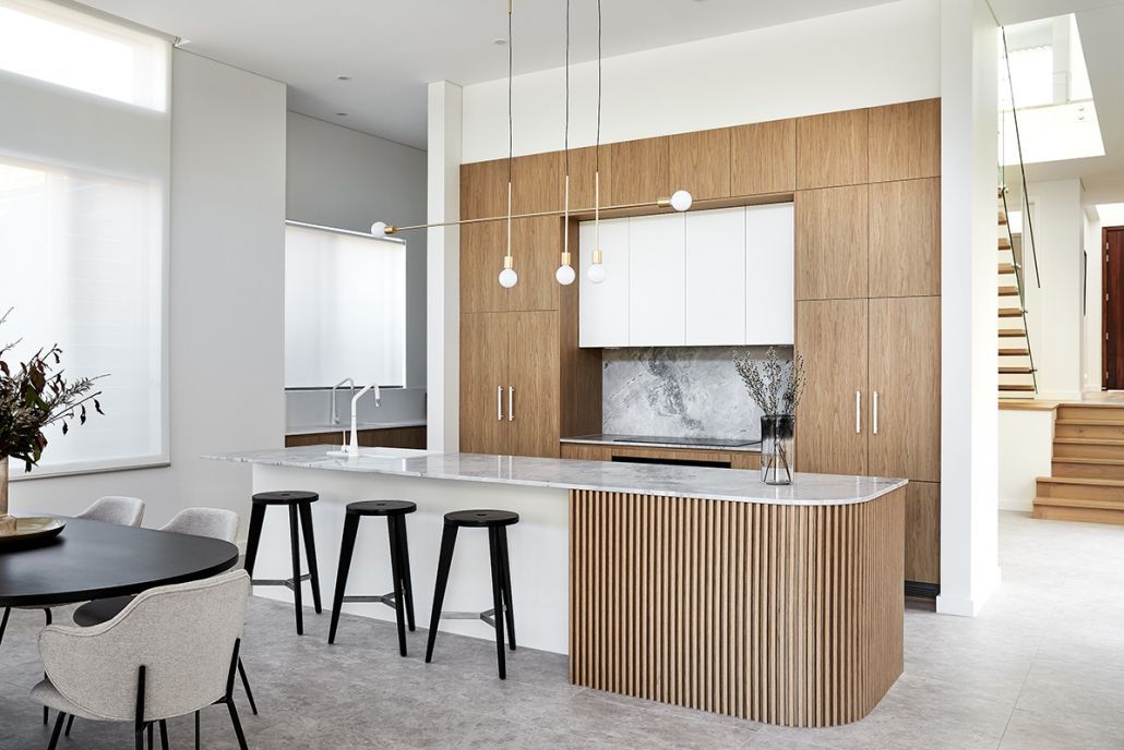 A kitchen with wooden cabinets , a large island , a table and chairs.