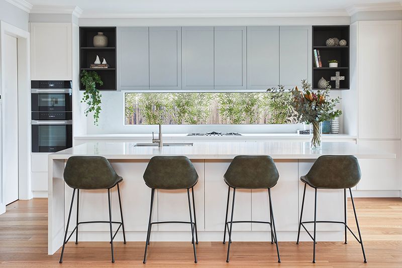 A kitchen with a large island and four bar stools.