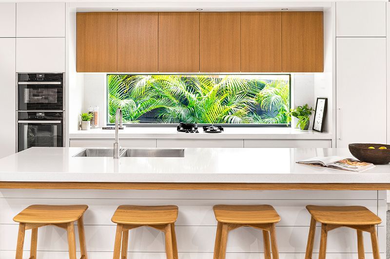 A kitchen with a large island , stools , a sink and a window.