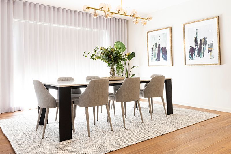 A dining room with a table and chairs and a rug.