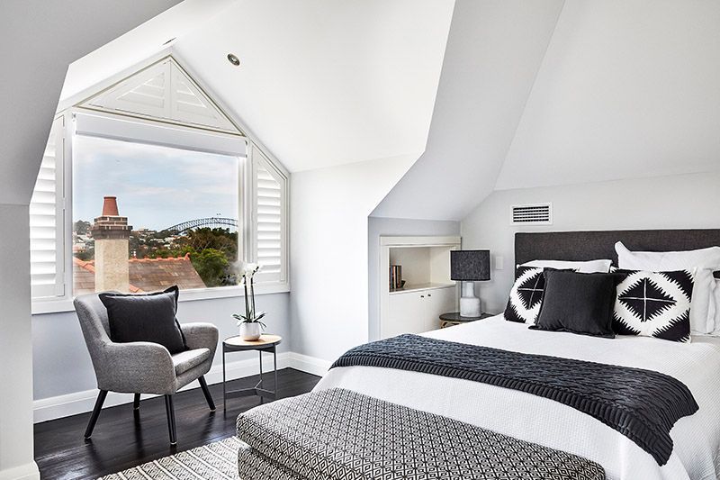 A bedroom with a bed , chair , table and window.