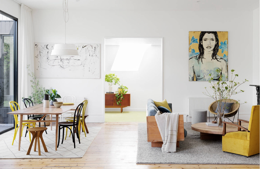 A living room with a table and chairs and a painting on the wall.