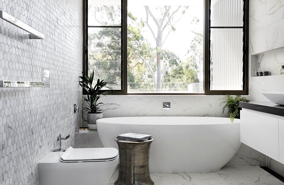 A bathroom with a tub , toilet , sink and window.