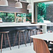 A kitchen with a long counter , stools , a table and chairs.