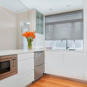 A kitchen with white cabinets , stainless steel appliances , a microwave , a sink and a window.