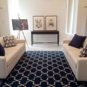 A living room with two couches and a blue rug.