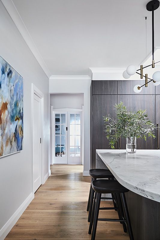 A kitchen with a large island and stools and a painting on the wall.