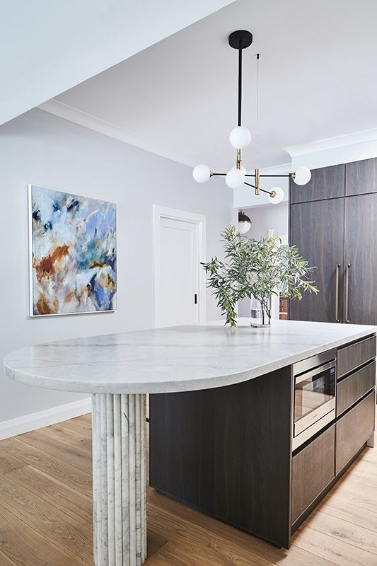 A kitchen with a large island and a painting on the wall.
