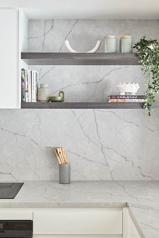 A kitchen with white cabinets and a marble counter top.