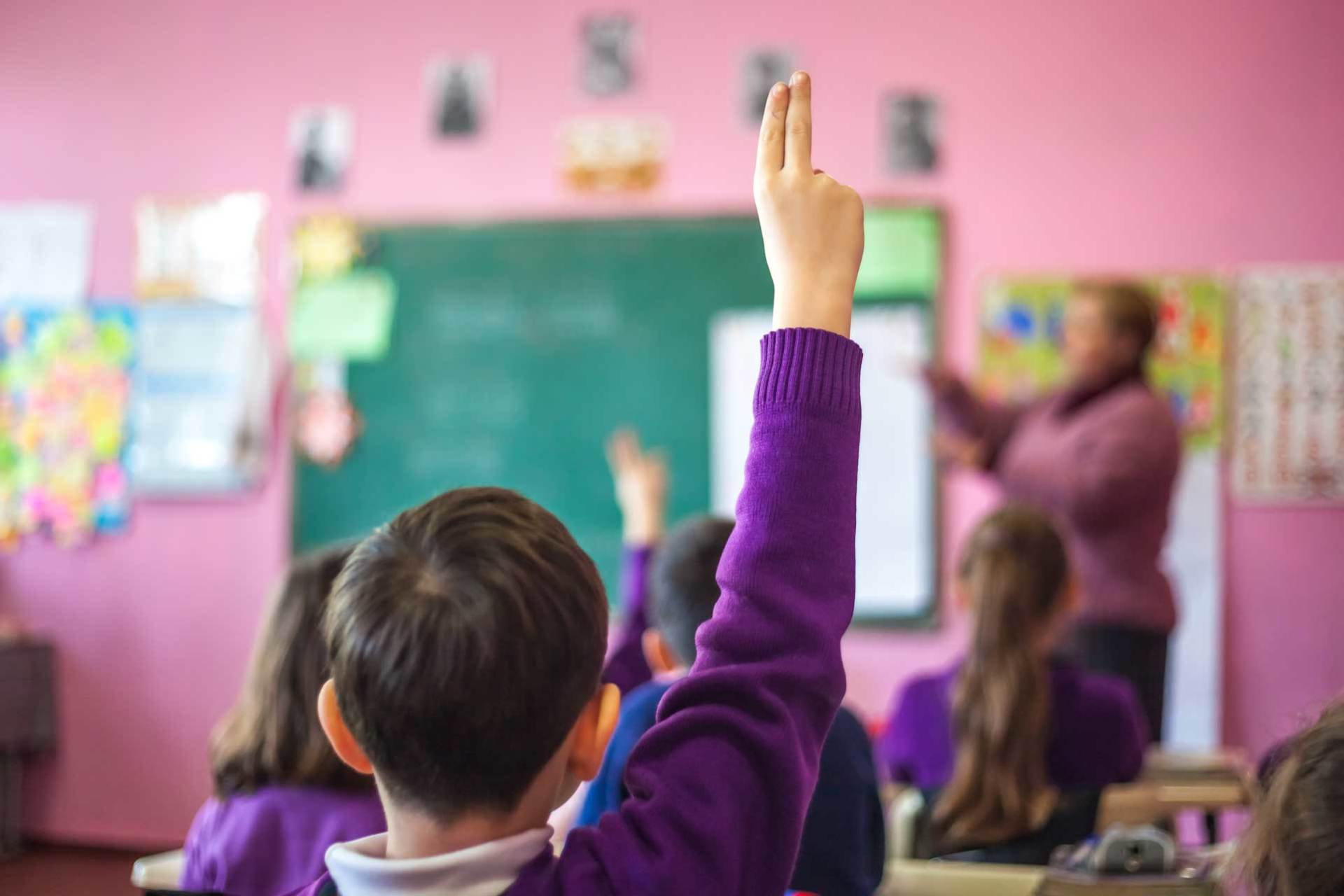 kids in classroom with hands raised