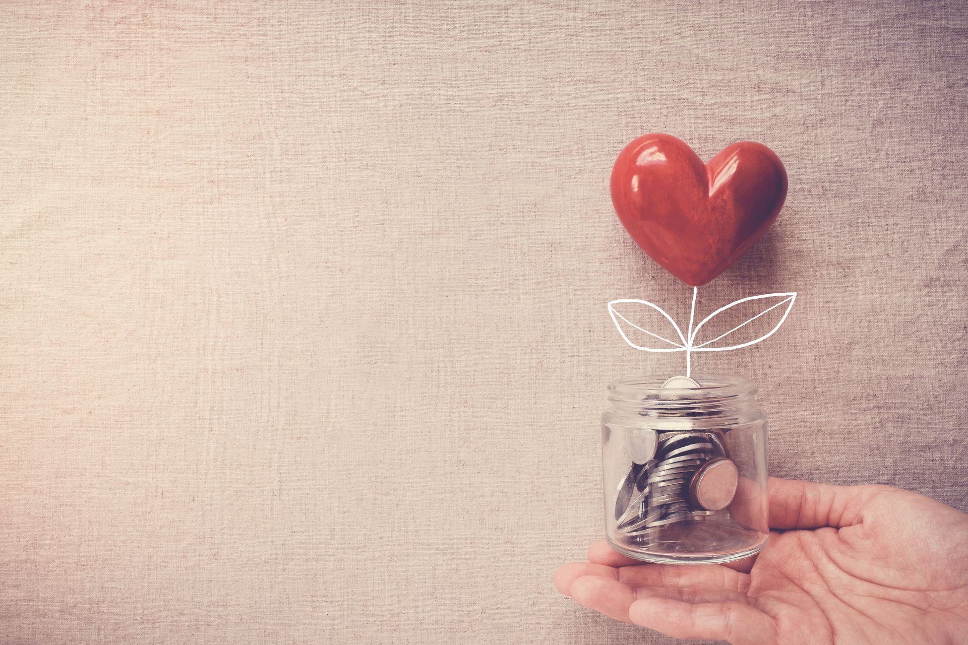 hand holding jar full of coins with a heart growing out of it (drawn)