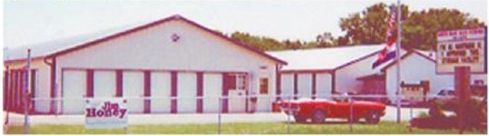 A red car is parked in front of a building that says molly A red car is parked in front of a building that says molly