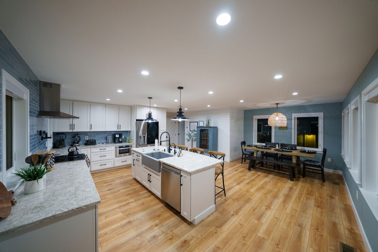 Bright open-concept kitchen and dining area with white cabinets, island, and wood floors