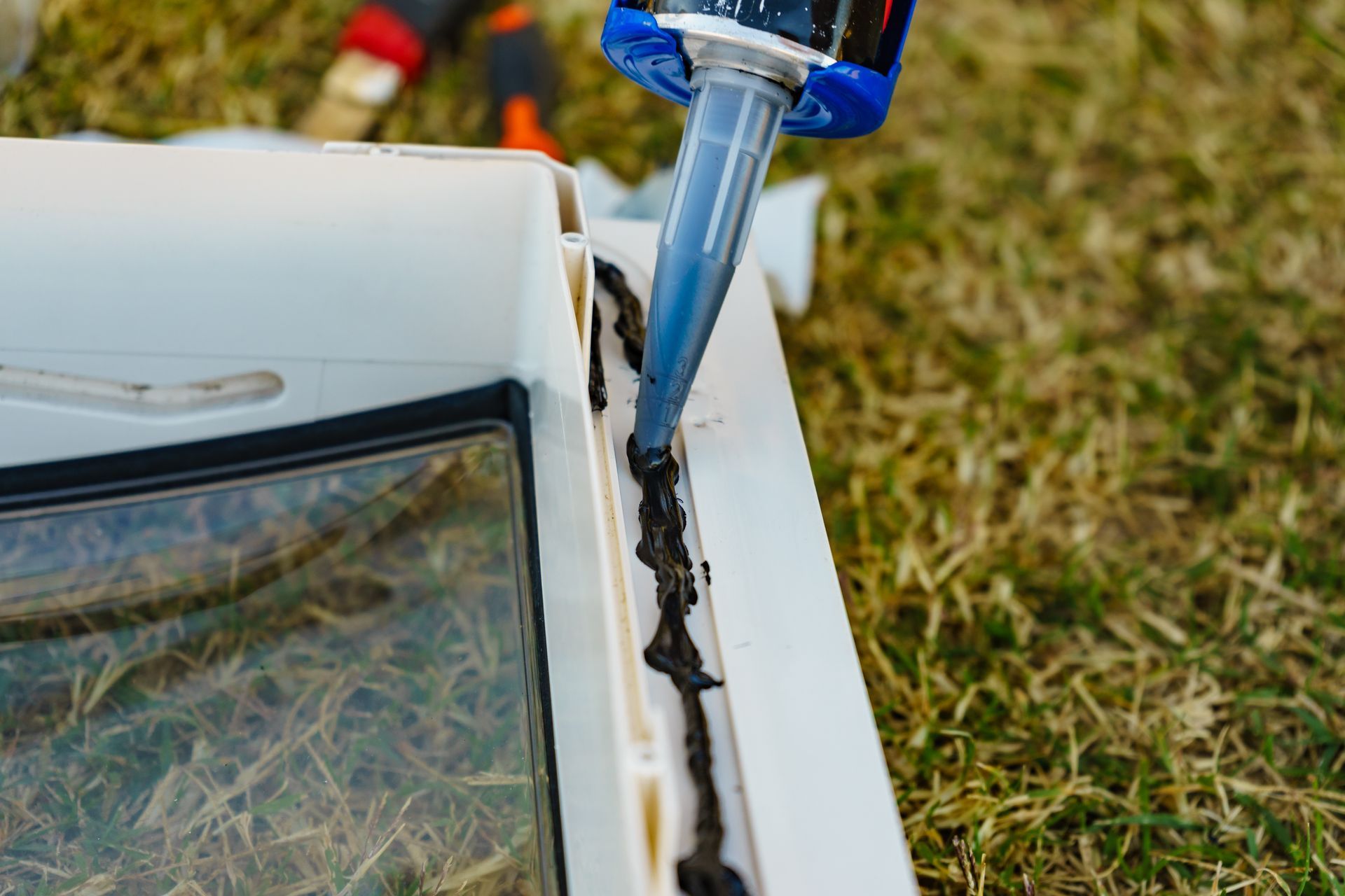A Person is Applying Silicone Sealant to a Window — Darwin Caravan & RV Centre In Berrimah, NT
