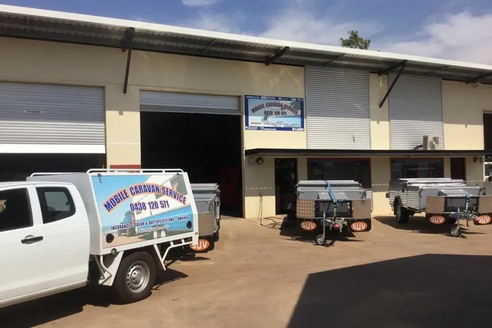 A White Truck is Parked in Front of a Building With Trailers — Darwin Caravan & RV Centre In Berrimah, NT
