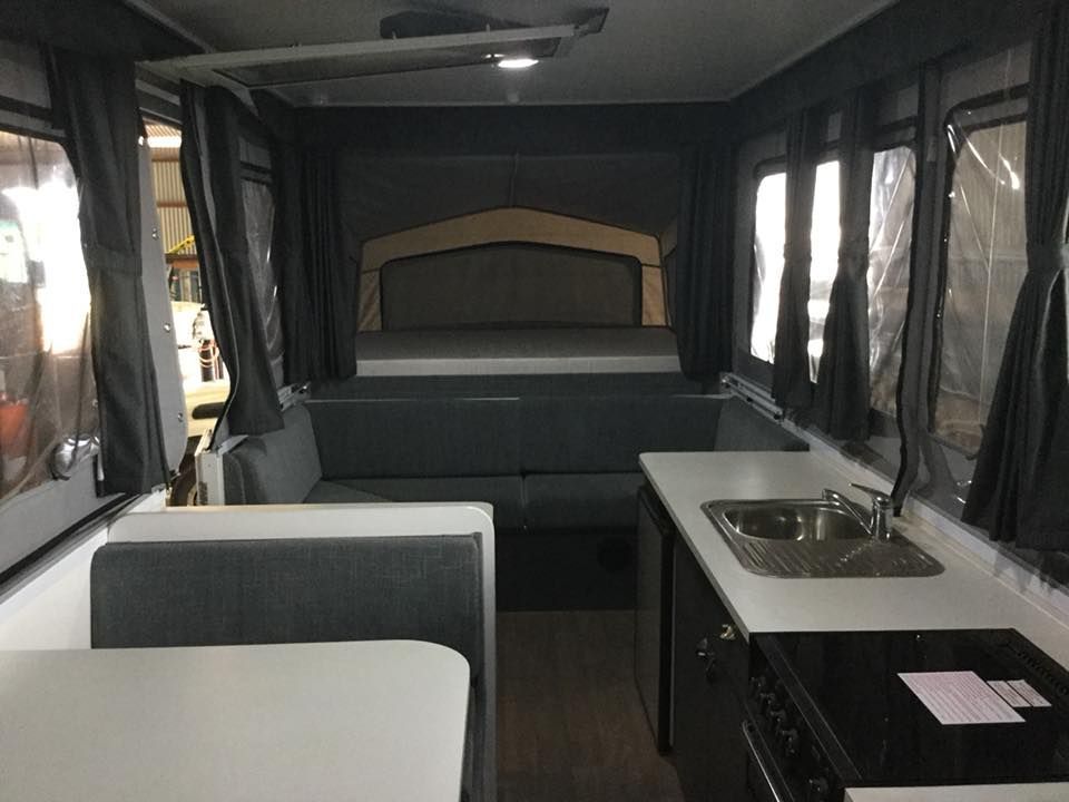 The Inside of a Camper With a Couch, Table, Sink and Bed — Darwin Caravan & RV Centre In Lee Point, NT
