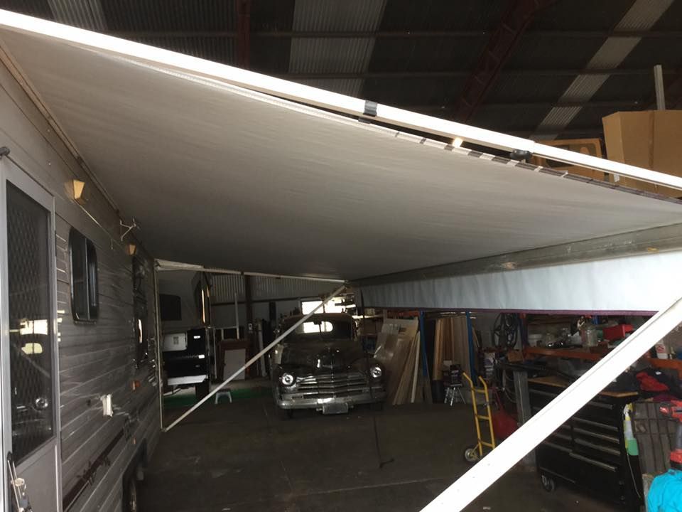 RV with extended white awning over a car in a garage- — Darwin Caravan & RV Centre In Berrimah, NT