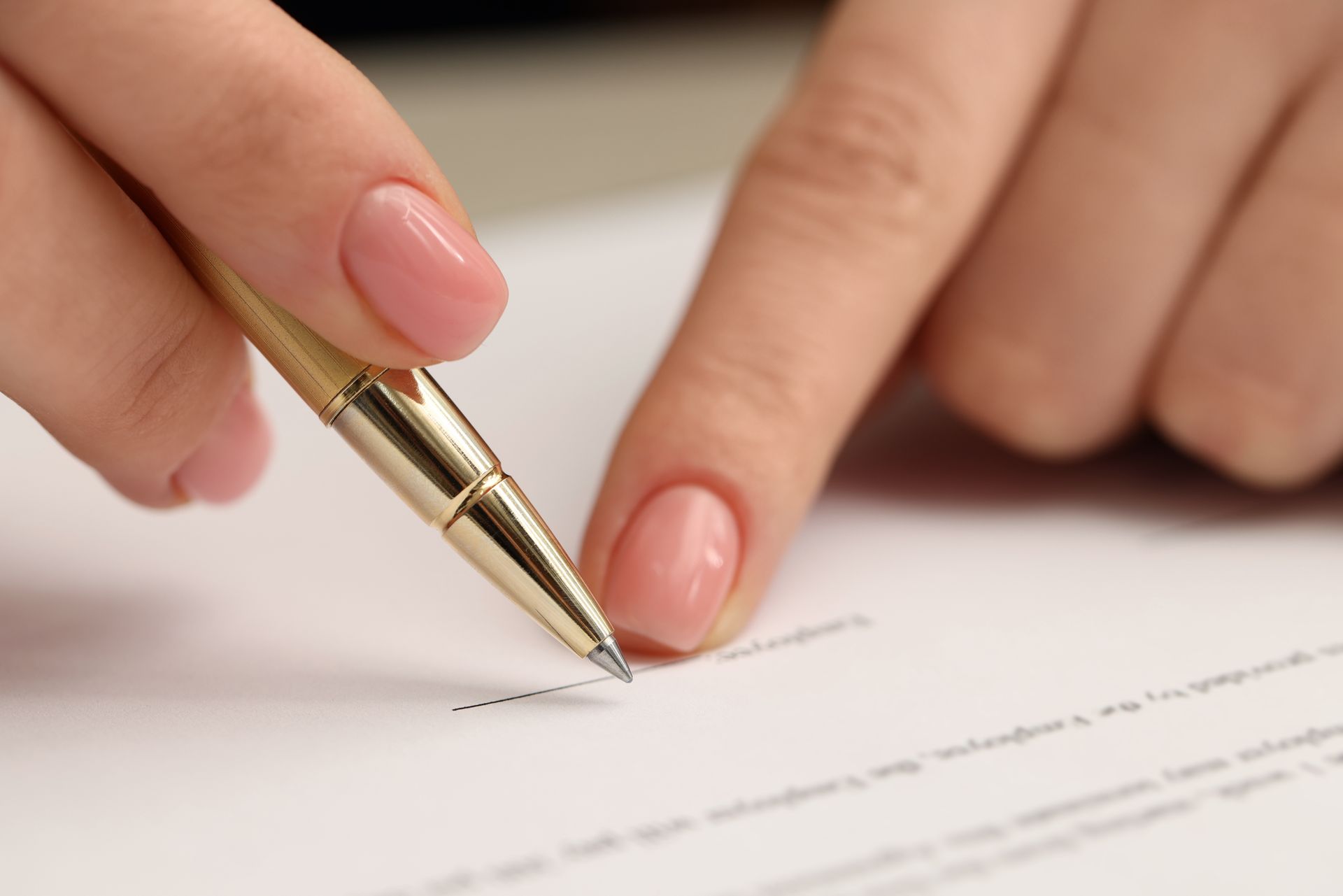 Person's hand with pink nails pointing at pen tip on a white document, ready to write.