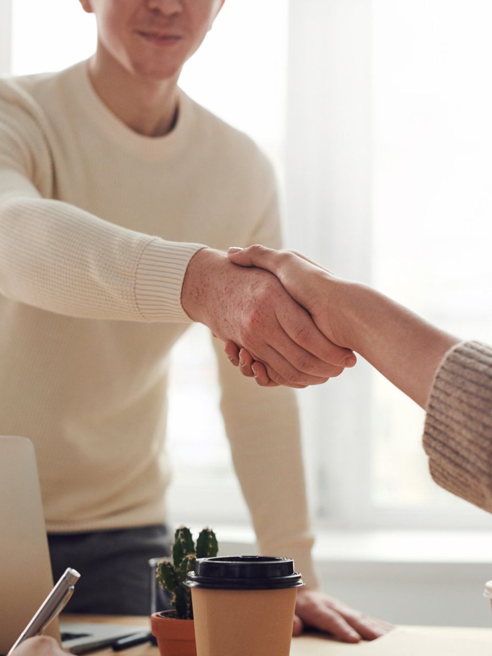 A man and a woman are shaking hands over a table.