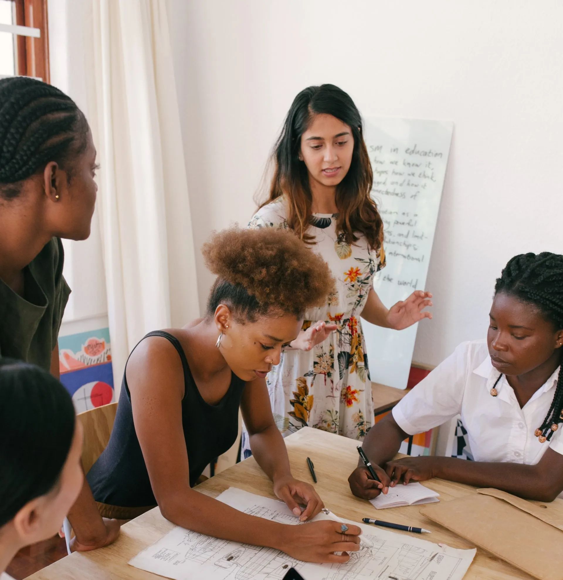 A group of women are sitting at a table writing on papers