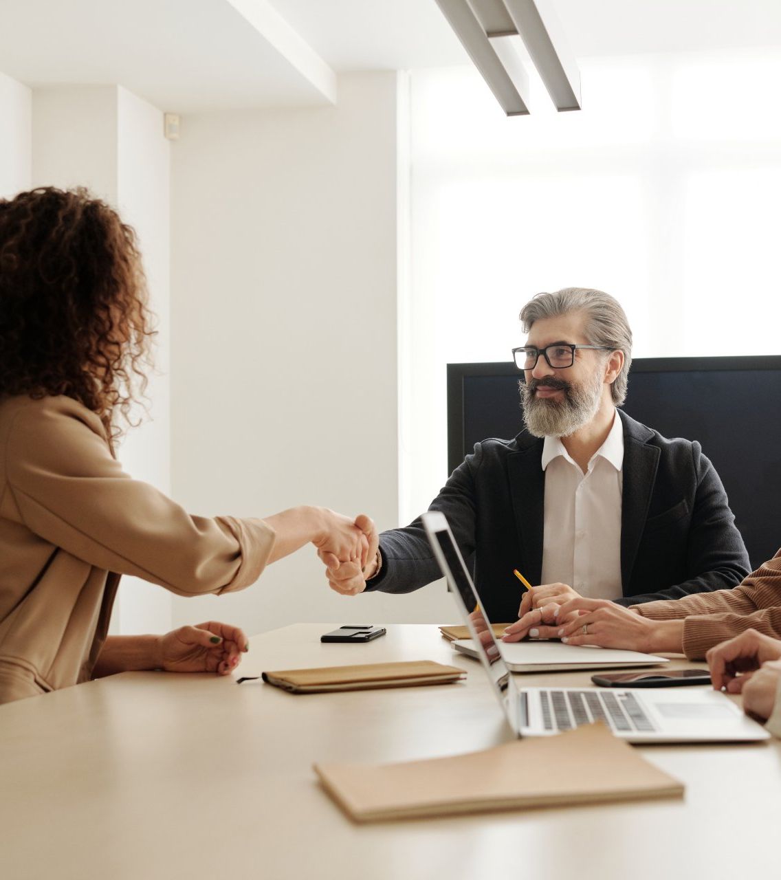 A group of people are sitting around a table shaking hands.