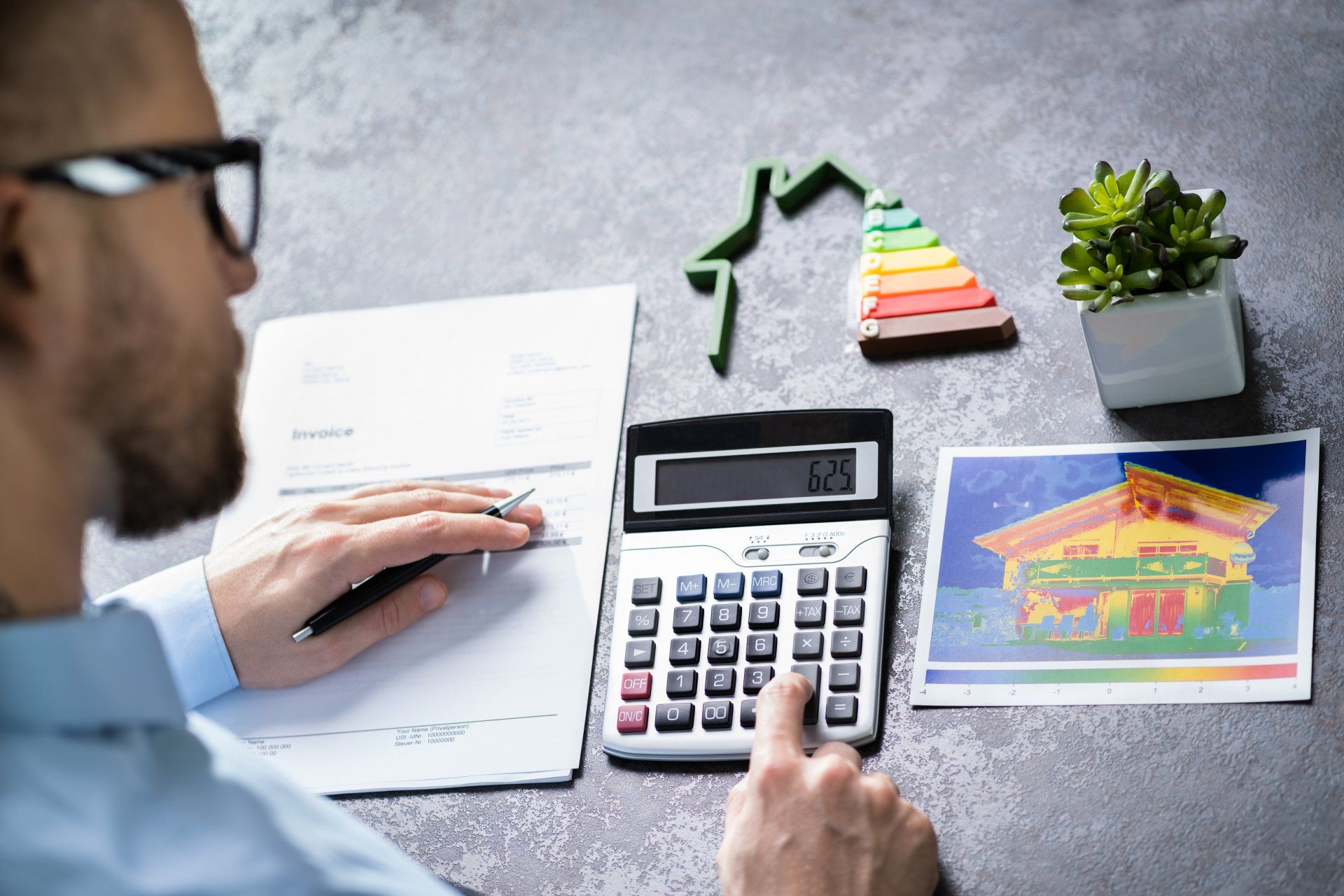Man Calculating Financial Data With House Model Showing Energy Efficiency Rate On Desk