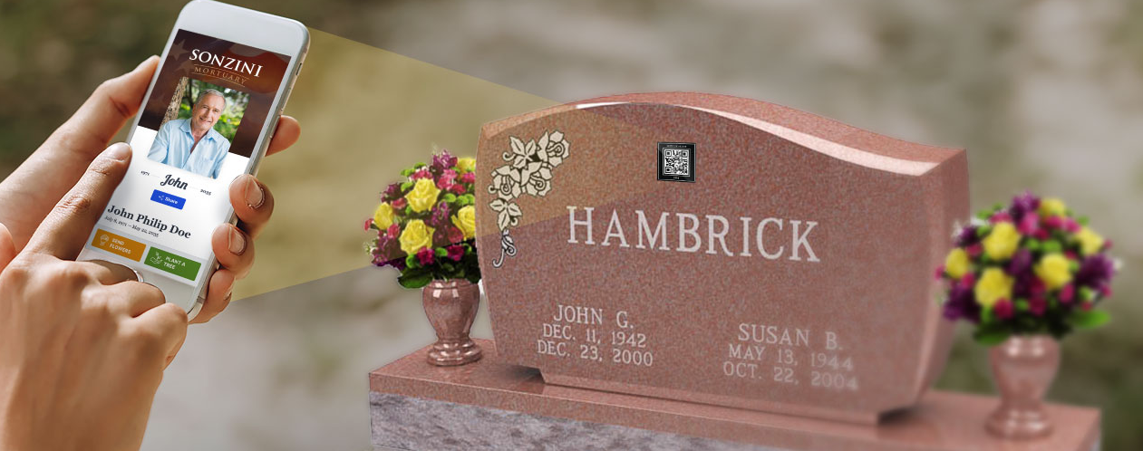 A person is holding a cell phone in front of a grave.