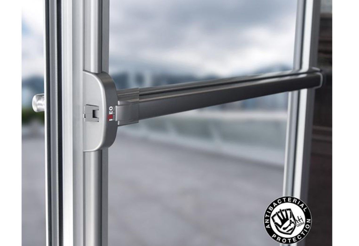 Close-up of a metal window handle on a glass door, with blurred outdoor background.