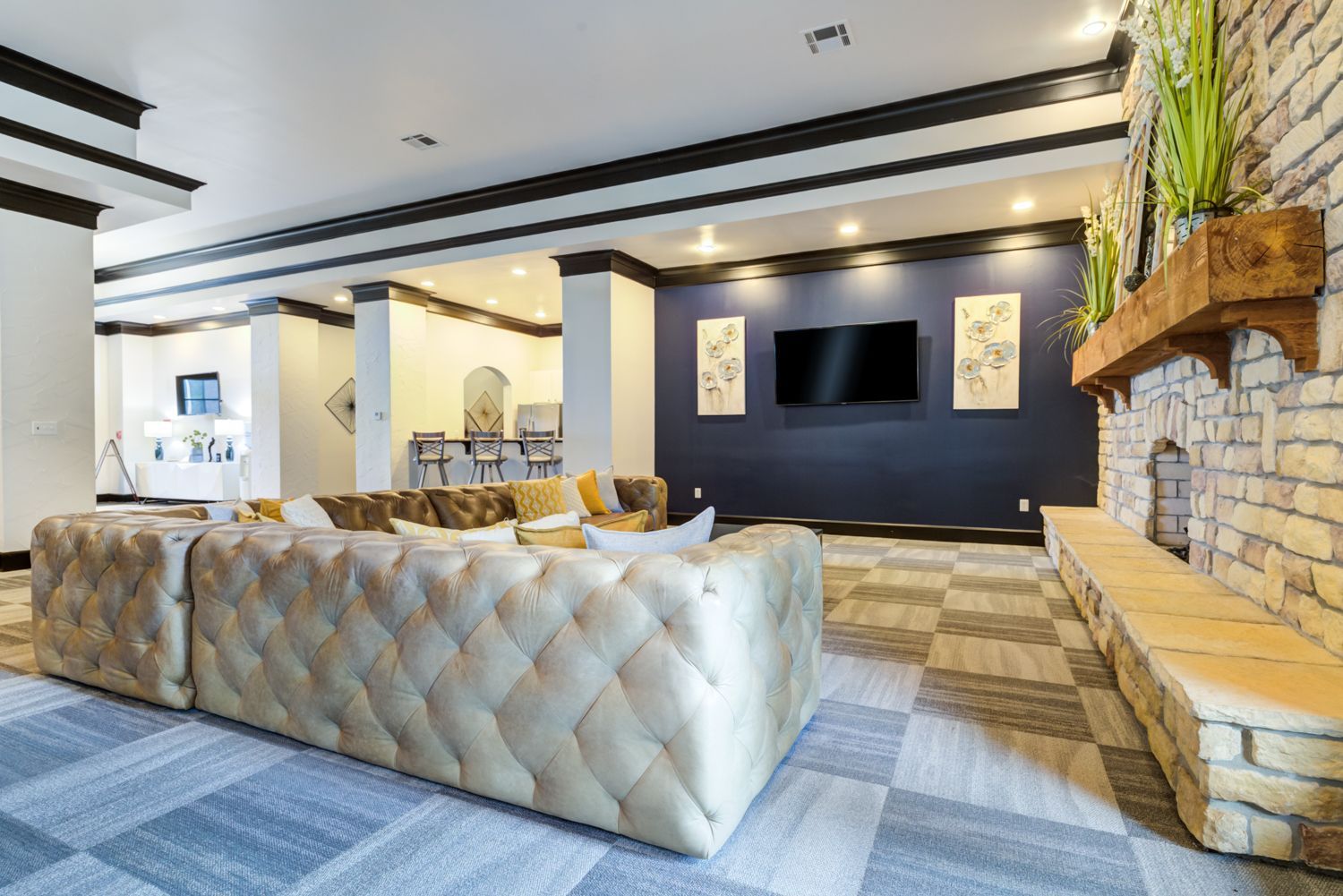 Lounge area with tufted sofa, TV, fireplace. Blue and white walls, gray checkered floor.