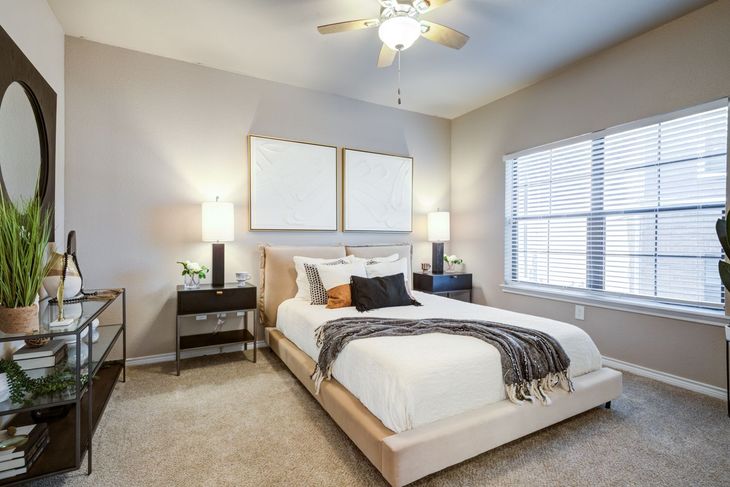 Bedroom with bed, nightstands, window, beige walls, and decor.