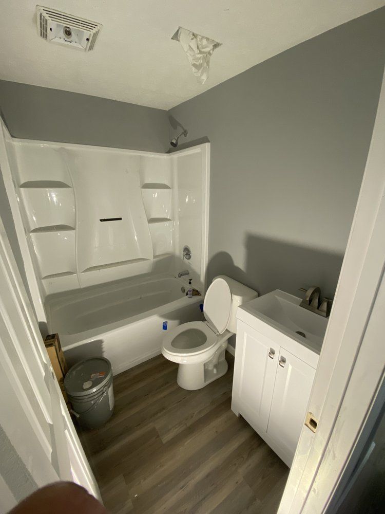 A bathroom with a toilet , sink and bathtub.