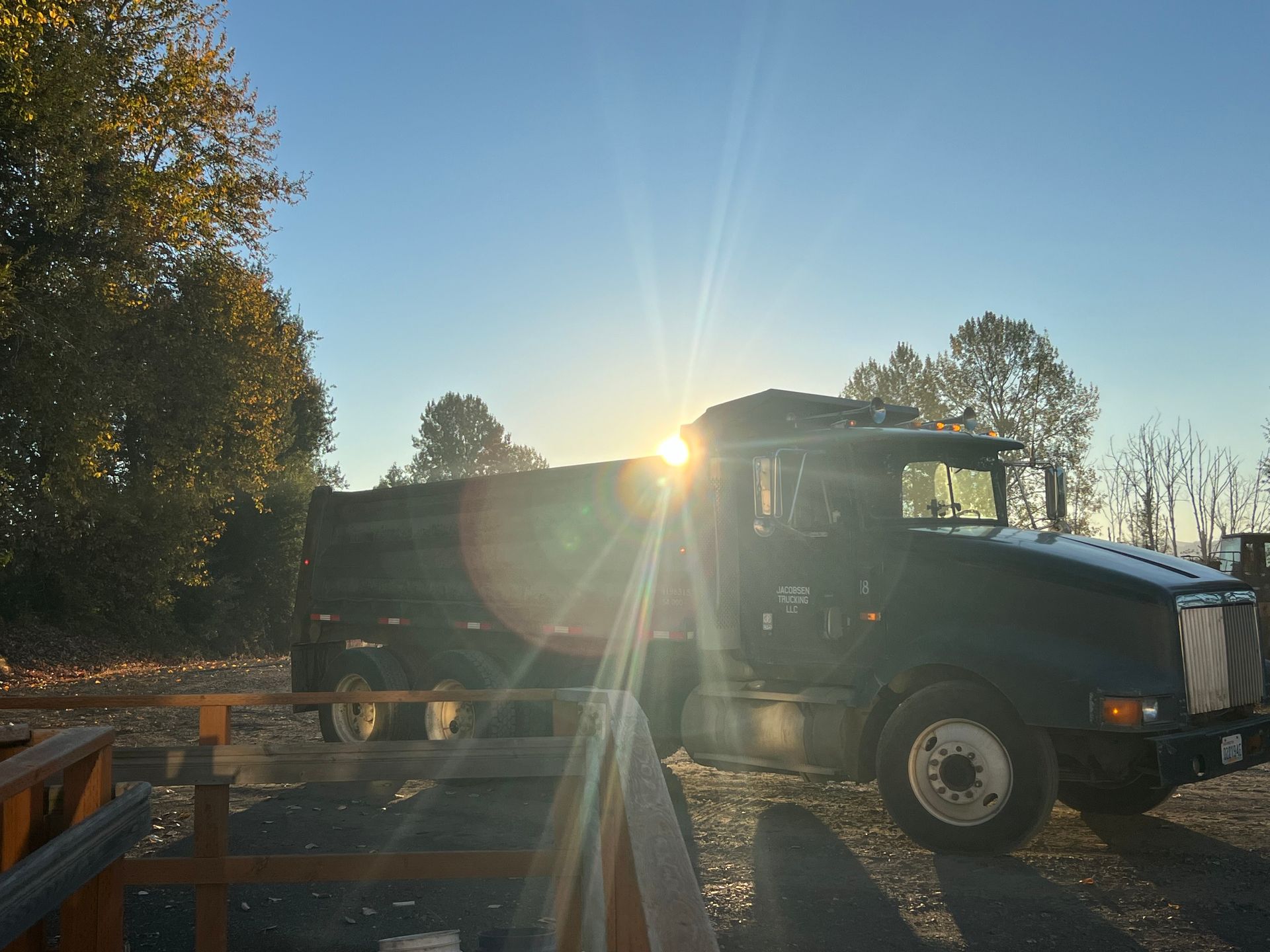A yellow hard hat and tools on a white table in a construction setting, with a person working in the background.