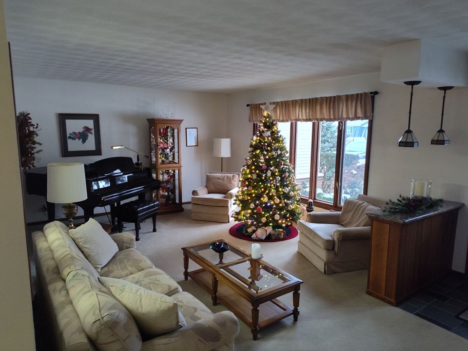 A living room with a piano and a christmas tree