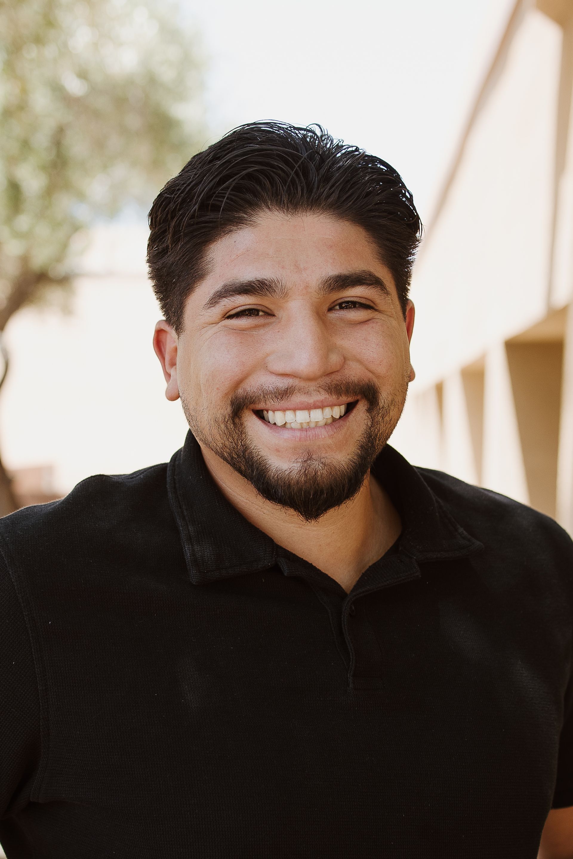 A man with a beard is smiling for the camera while wearing a black shirt.