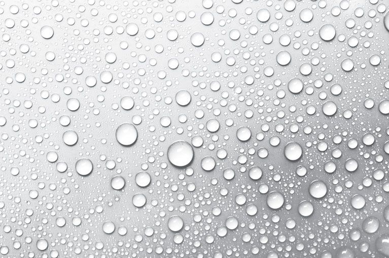 A close up of water drops on a white surface.