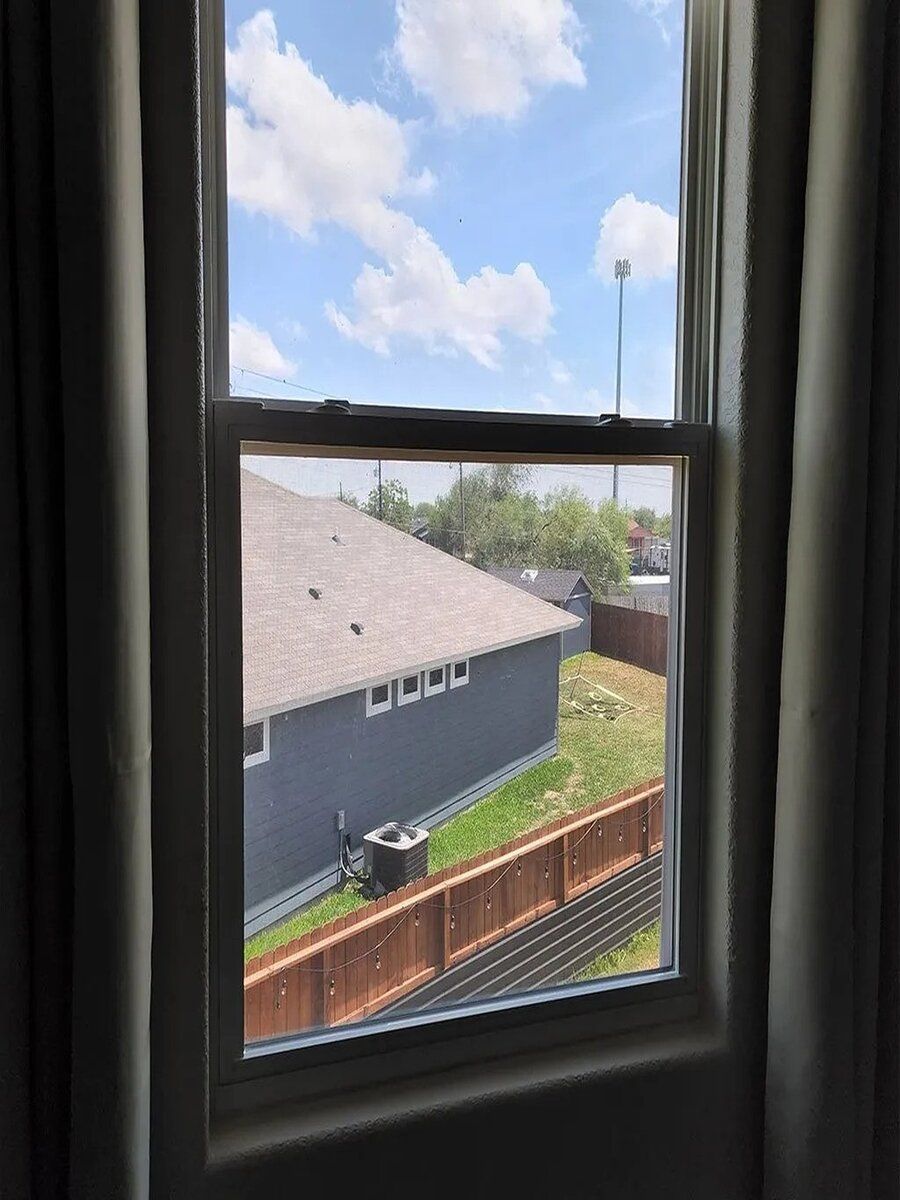 a window with a view of a house and a fence .