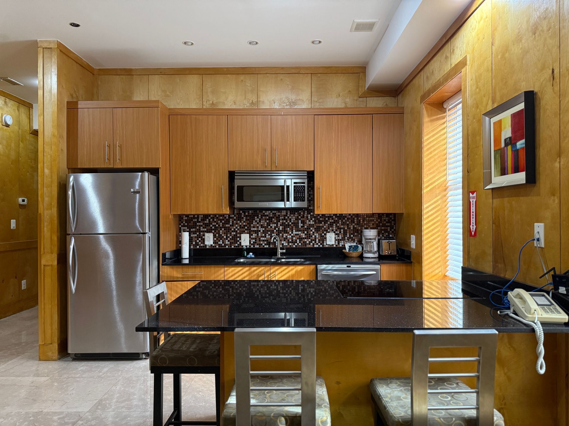 Kitchen with stainless steel appliances, dark countertop island, and wood cabinetry.