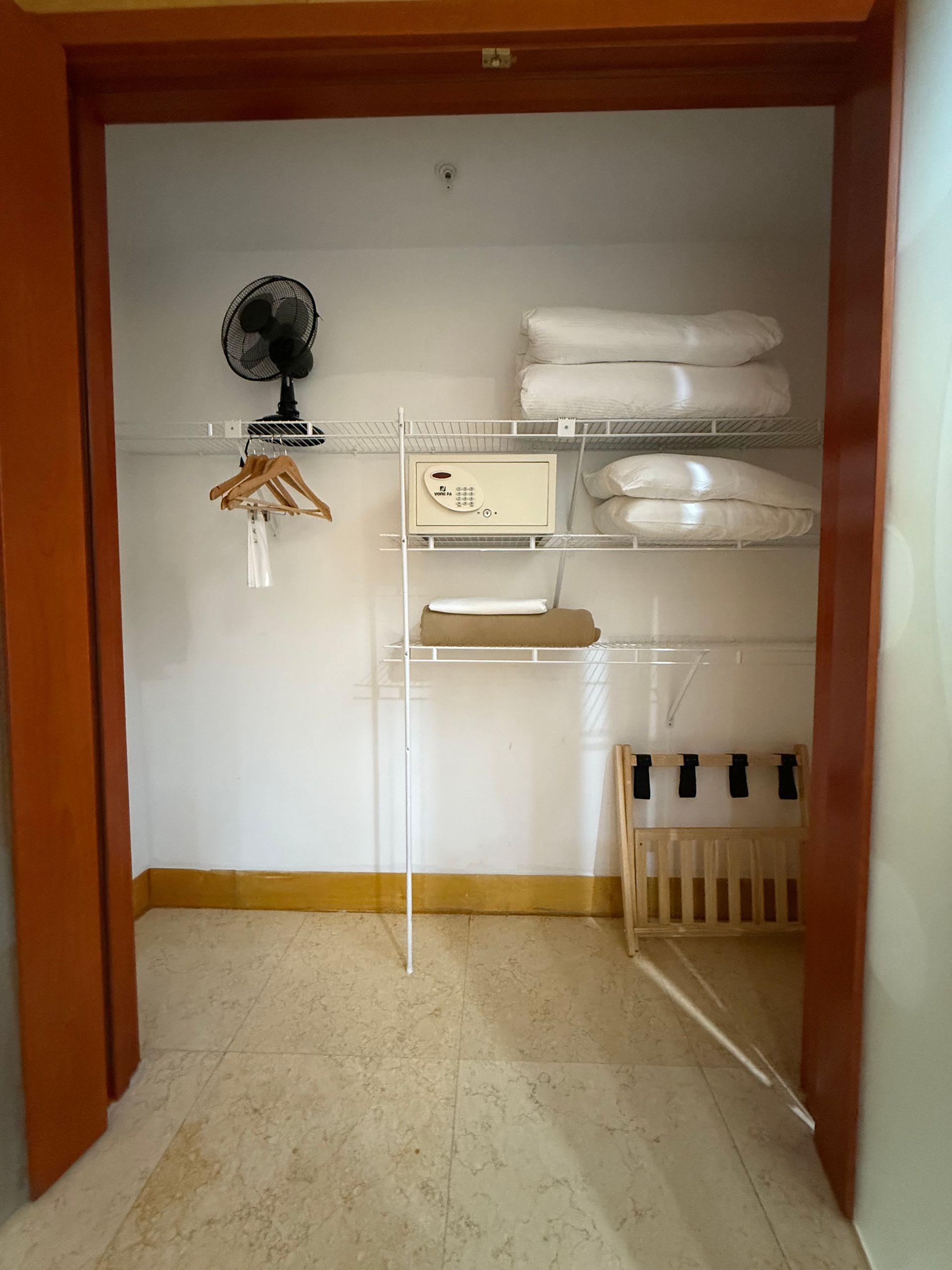Empty closet with wire shelves, fan, hangers, and shoe rack.