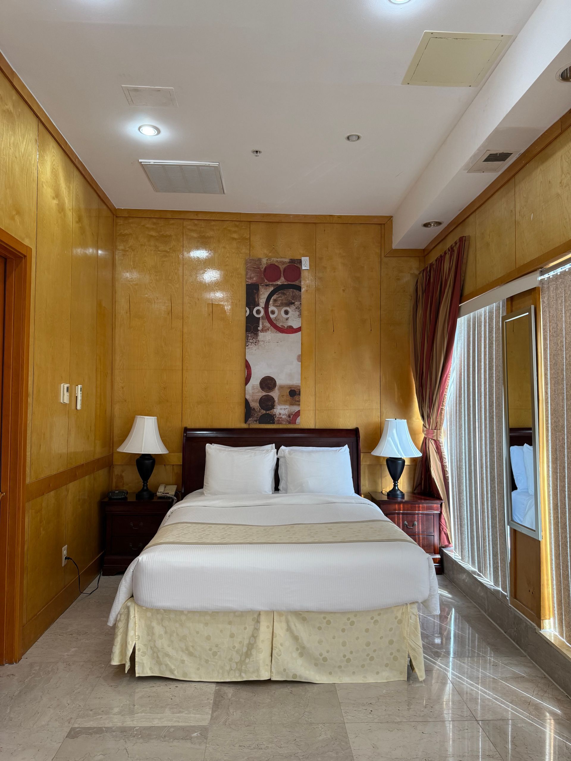 Bedroom with gold walls, a double bed with white bedding, and two bedside lamps.