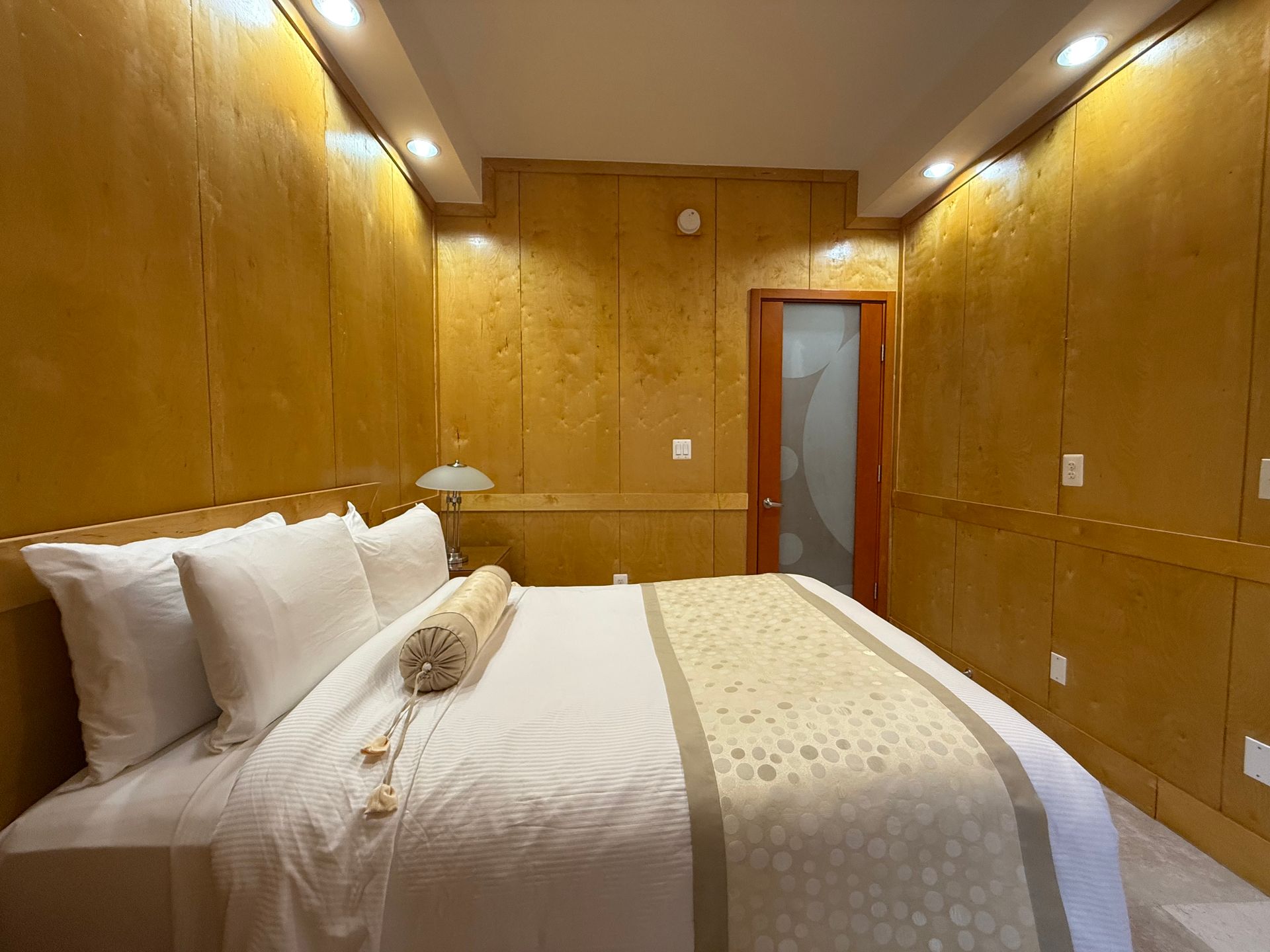 Bedroom with gold-toned walls, white bed linens, and a small door.