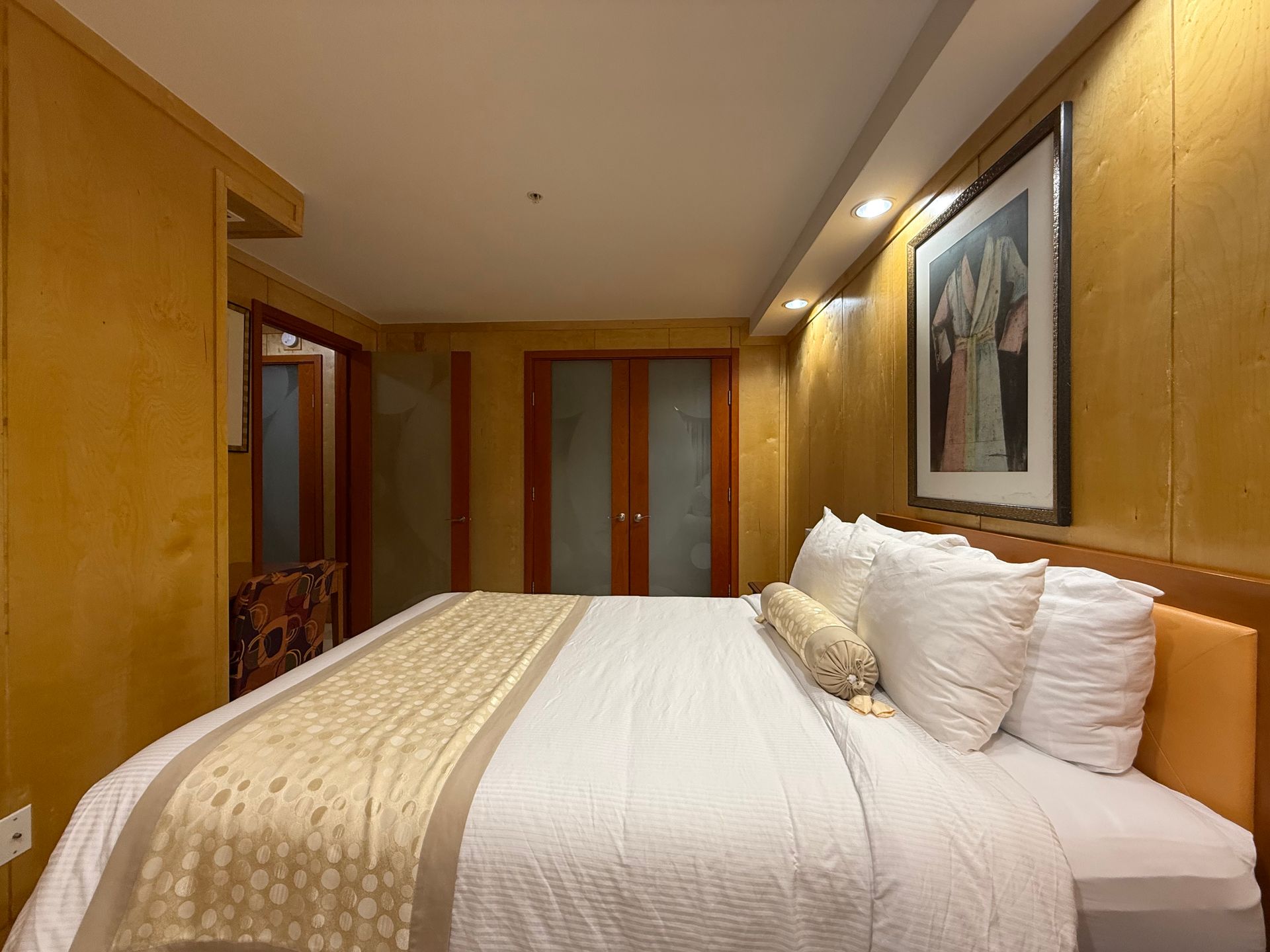 Bedroom with a large bed, featuring white bedding, and gold walls.