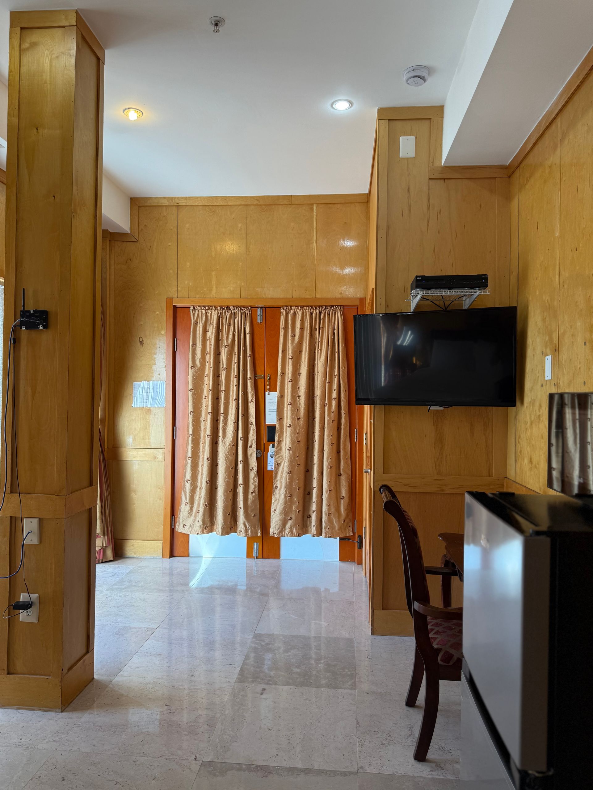 Interior with wood paneling, TV, chair, and doorway with curtains.