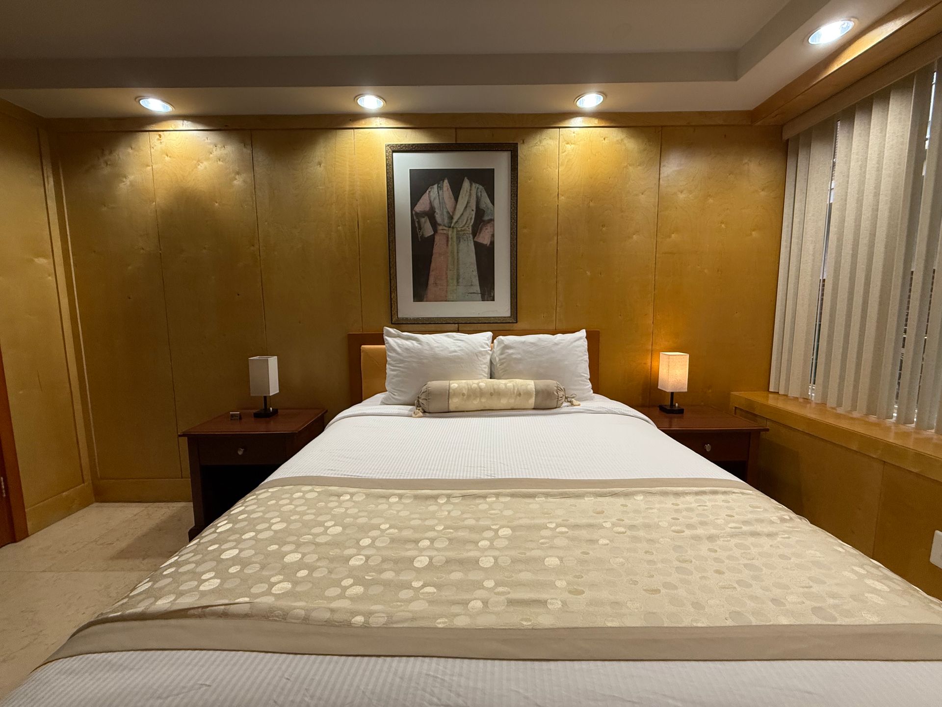 Bedroom with gold textured walls, a bed with white bedding, and artwork above the headboard.
