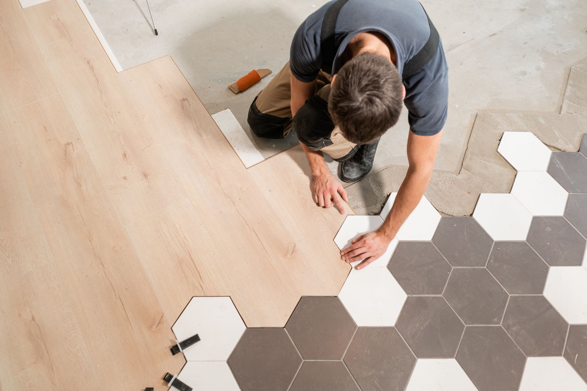 A man is installing a wooden floor with hexagonal tiles.